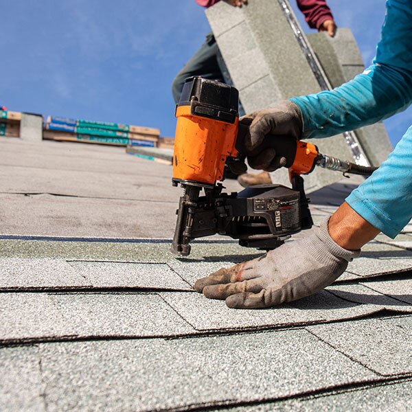 A roofer fastening shingles to a roof.