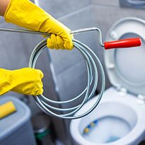 A person wearing yellow gloves ready to snack a toilet.