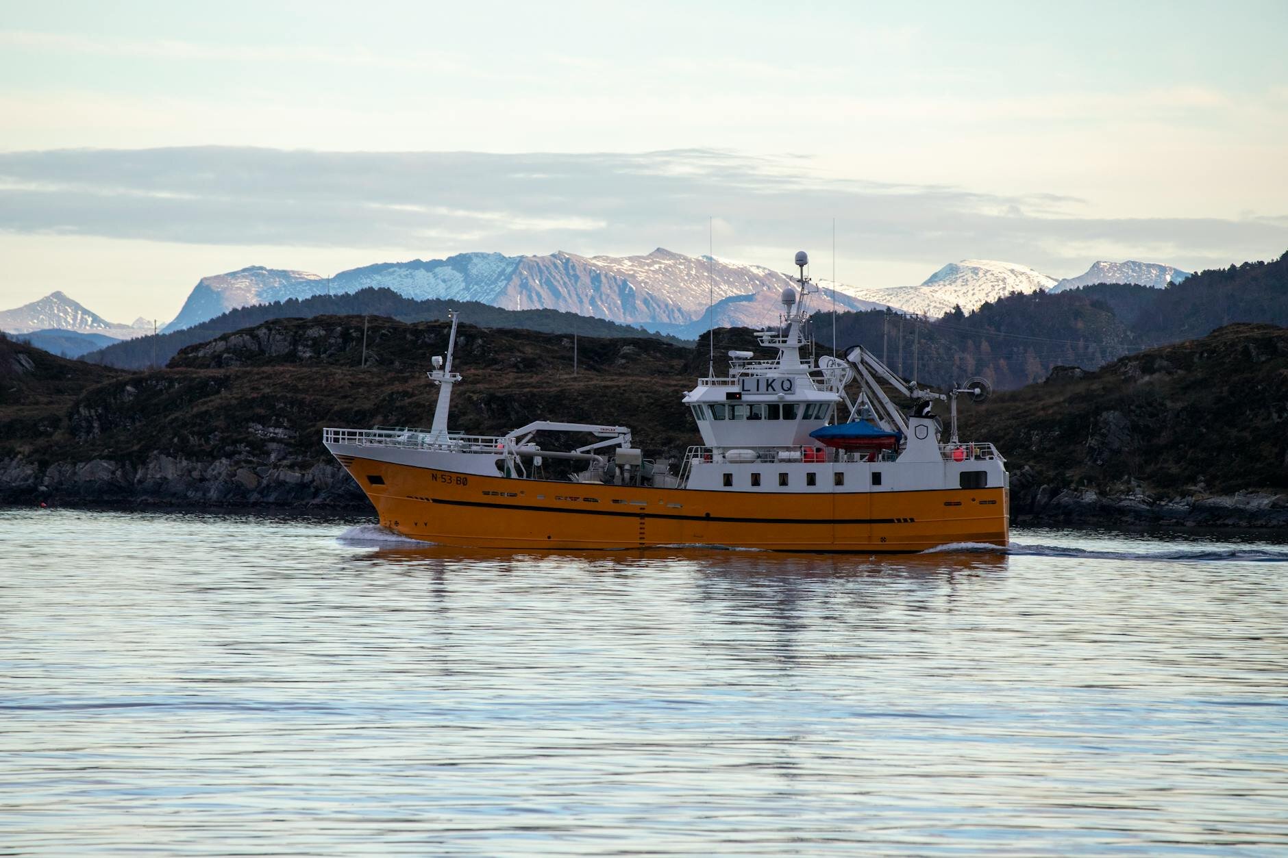 fishing boat sailing around mountain view