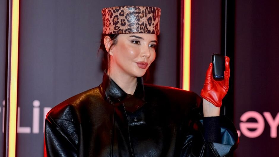 A female model wearing red gloves holds the Ploom product at the Ploom presentation.