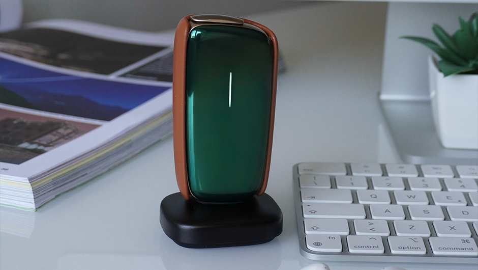 Green Ploom X Advanced device on a desk with keyboard, AirPods, and computer monitor in the background