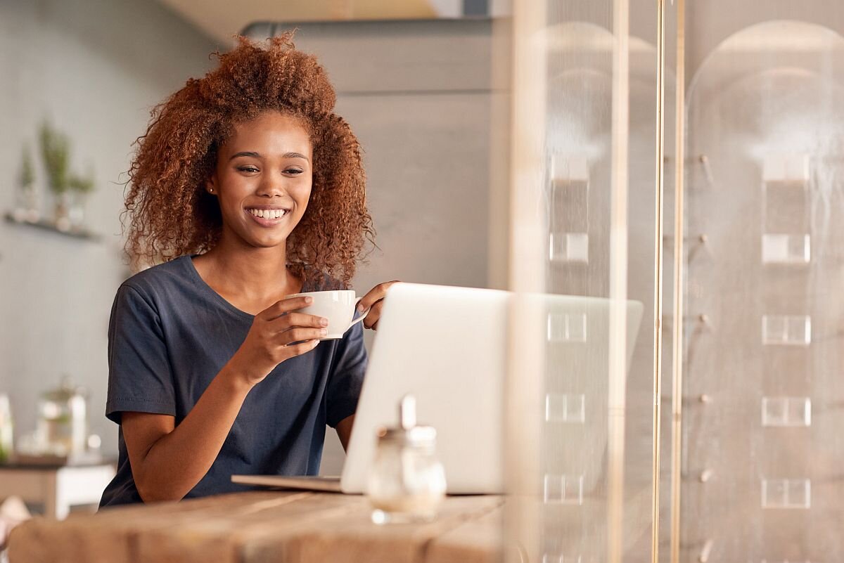 young woman working on a laptop and drinking coffee