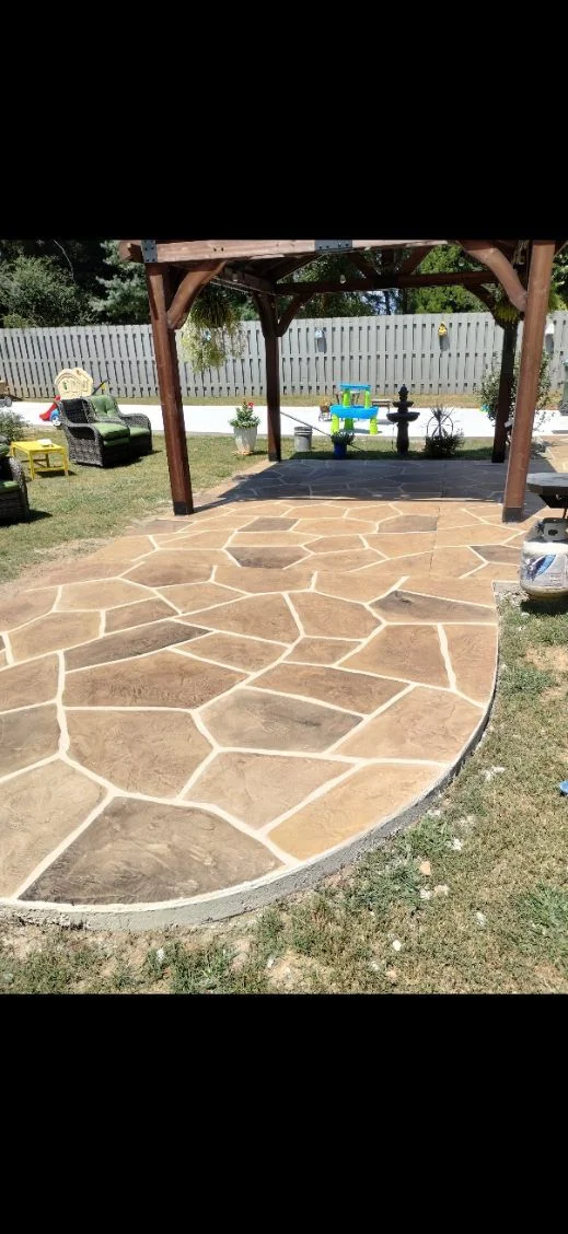 Warm flagstone-pattern concrete patio beneath a wood pergola
