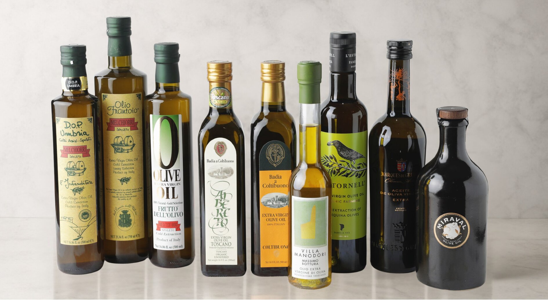 A lineup of extra virgin olive oil bottles from the De Medici portfolio on a marble surface