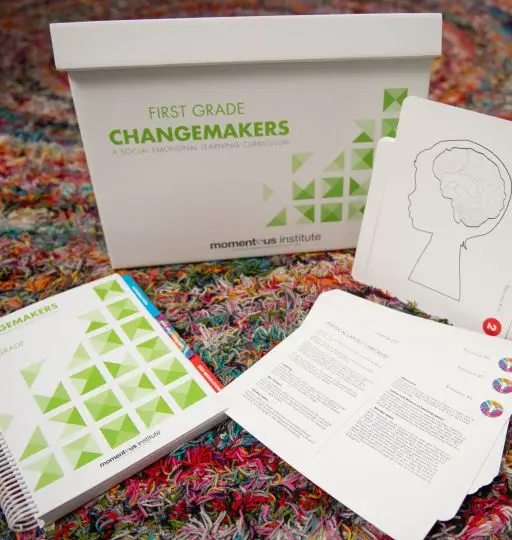 A Changemakers notebook and other papers on a carpet floor.