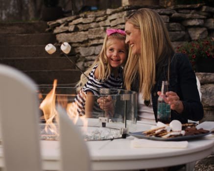 Woman and Young Girl Roasting Marshmallows on Fire Pit Table