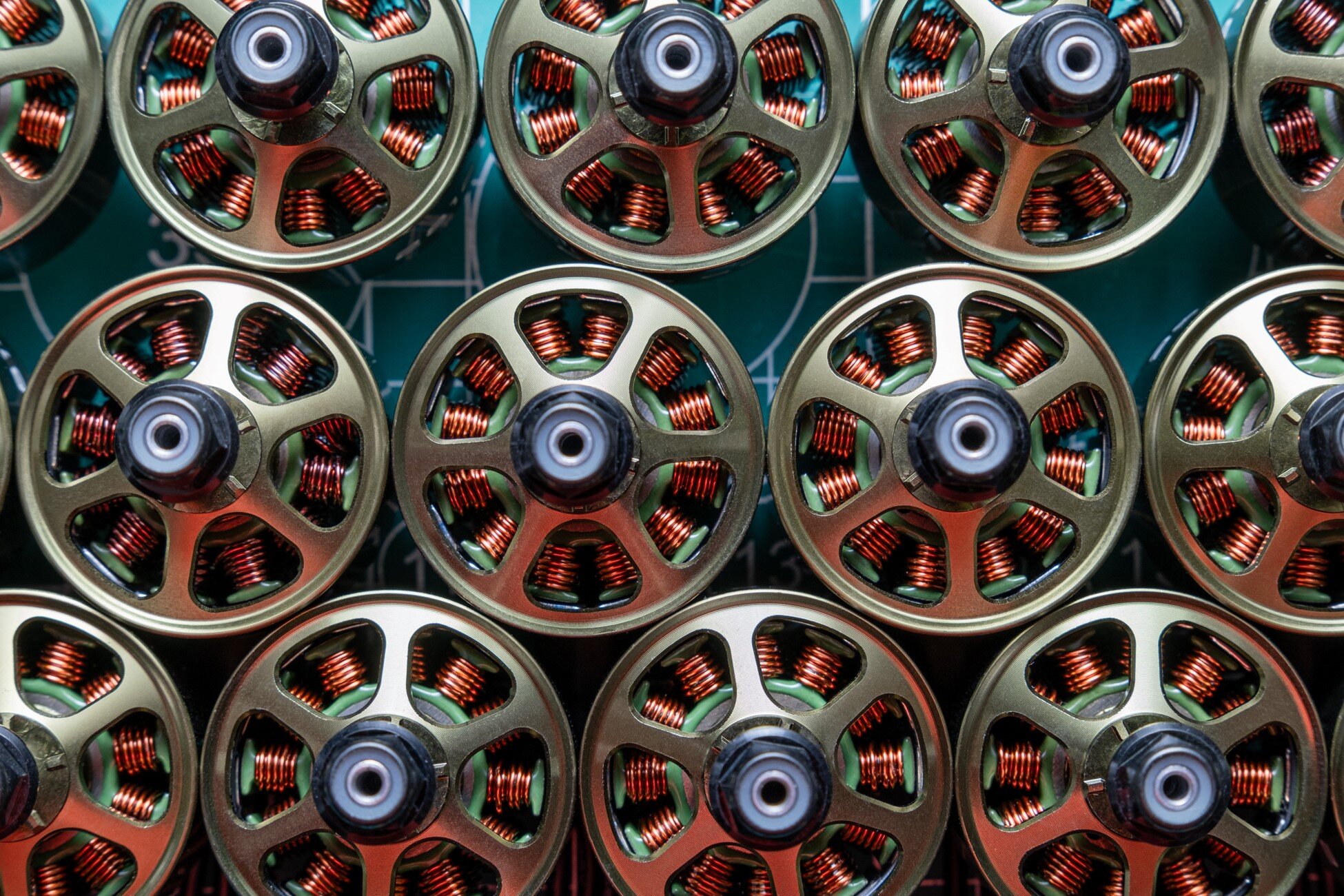 Multiple small electric motors with copper magnet wire coils, arranged in a grid pattern for assembly or inspection.