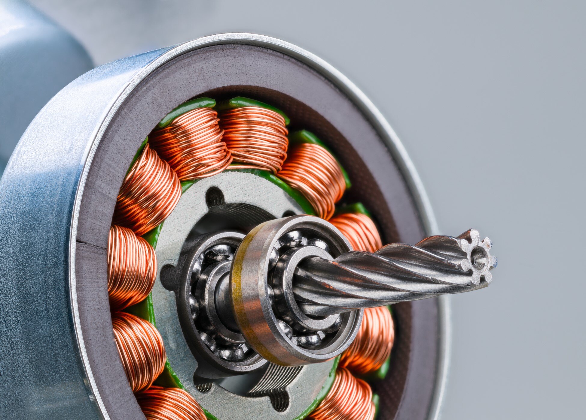 Close-up of copper magnet wire coils inside a precision electric motor with visible rotor and ball bearings.