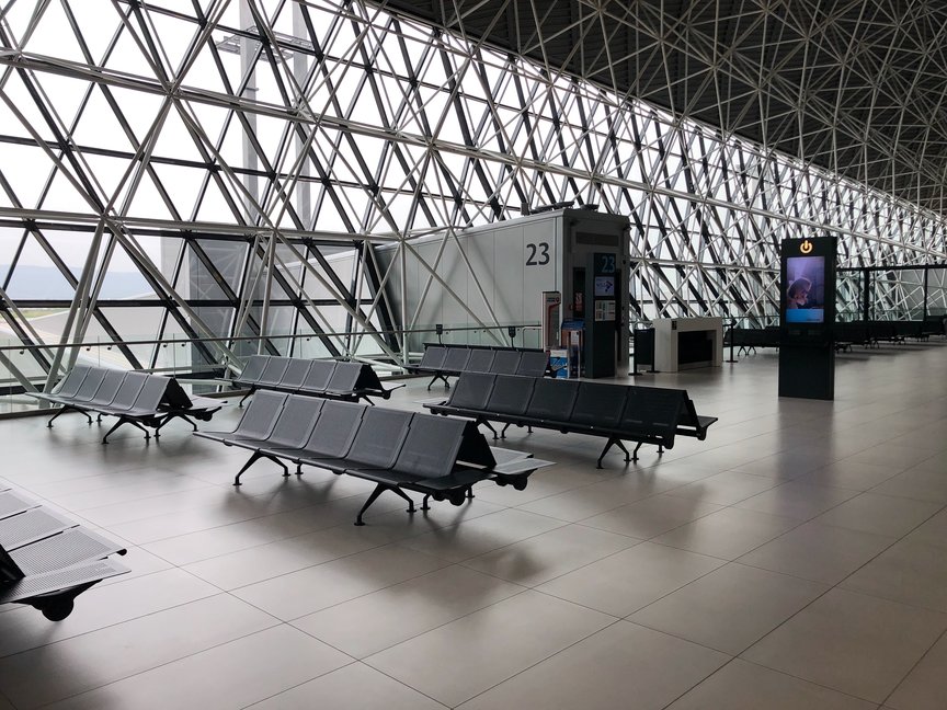 Empty chairs in airport waiting area with view of runway