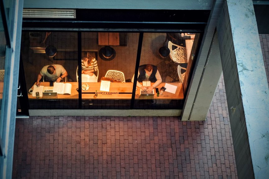 Three people sit at a co-working space desk, seen from above
