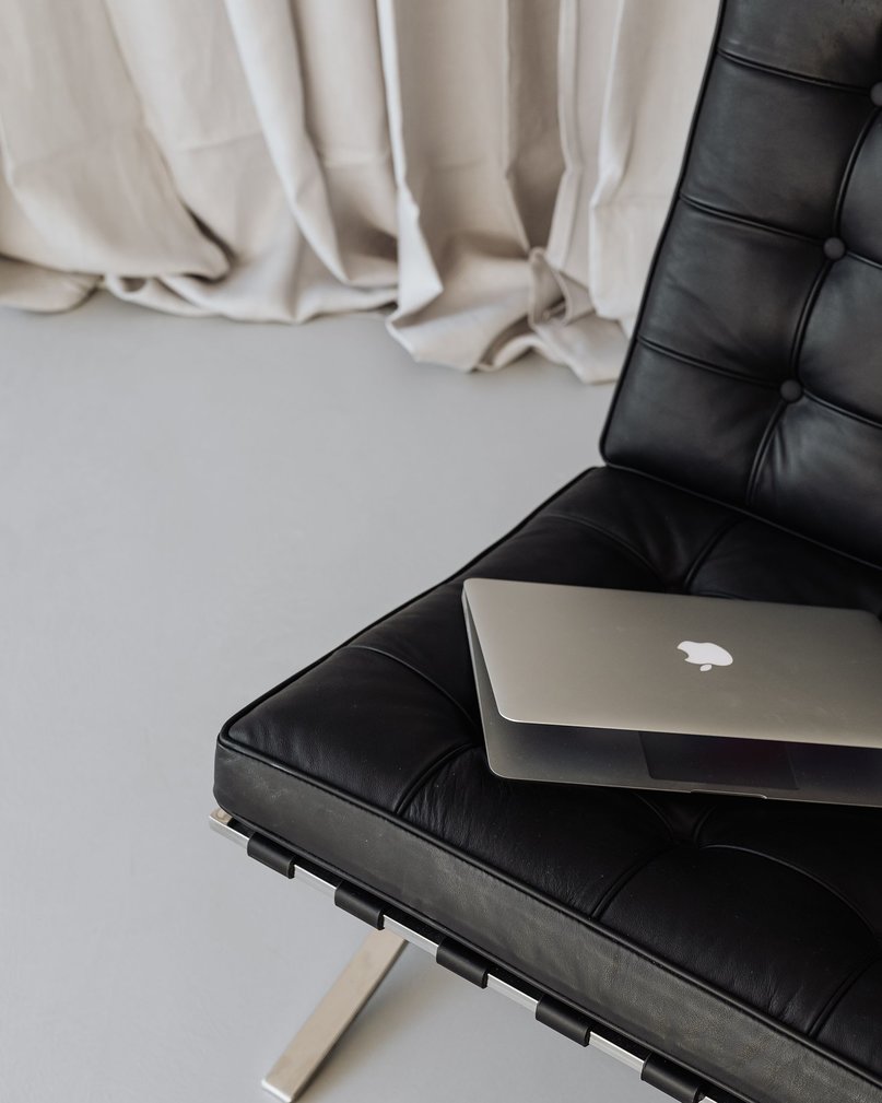 MacBook placed on black PU leather sofa