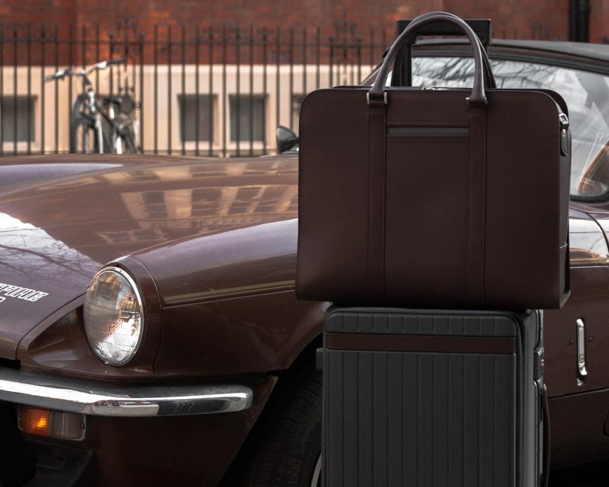 Carl Friedrik briefcase and suitcase standing beside a brown classic car