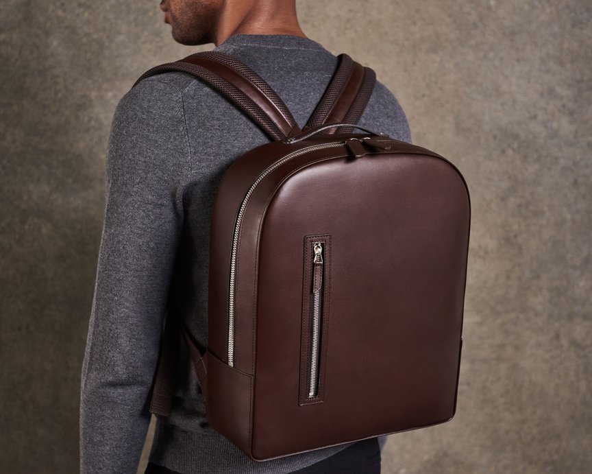 Model styles brown leather backpack by Carl Friedrik on back