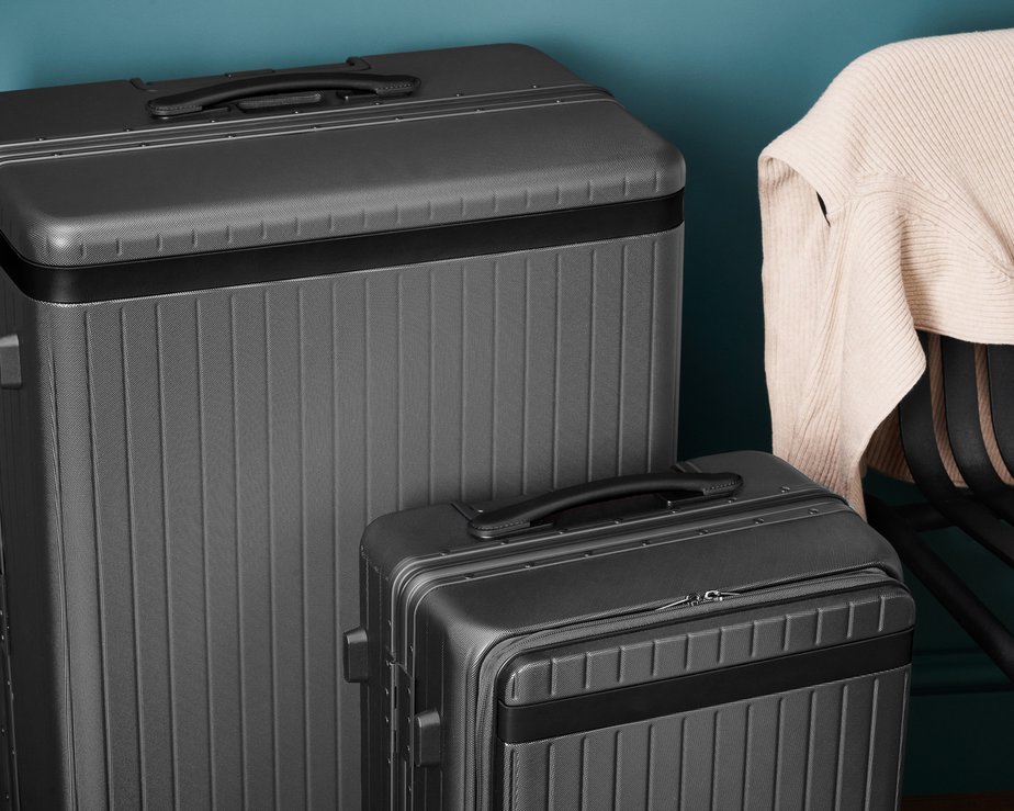 Two grey polycarbonate suitcases of varying sizes standing next to each other
