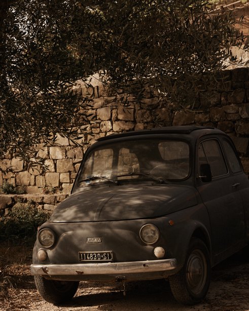 Vintage grey car in the shade below a tree in Tuscany