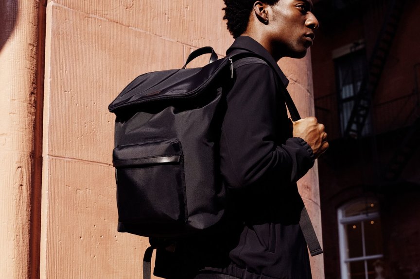 Man in black jacket wears black nylon backpack with stone background