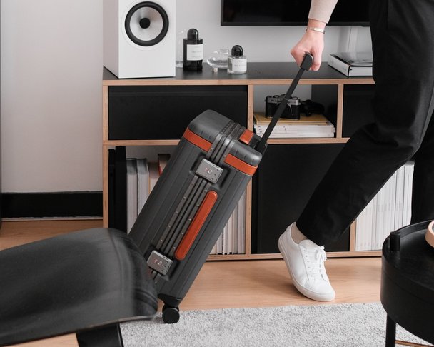 Bleisure traveller holding grey carry-on suitcase with camera round his neck