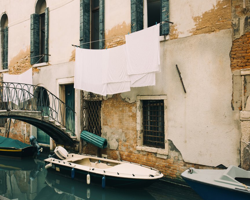 Towel hanging over the window and boats floating in the canal of Venice