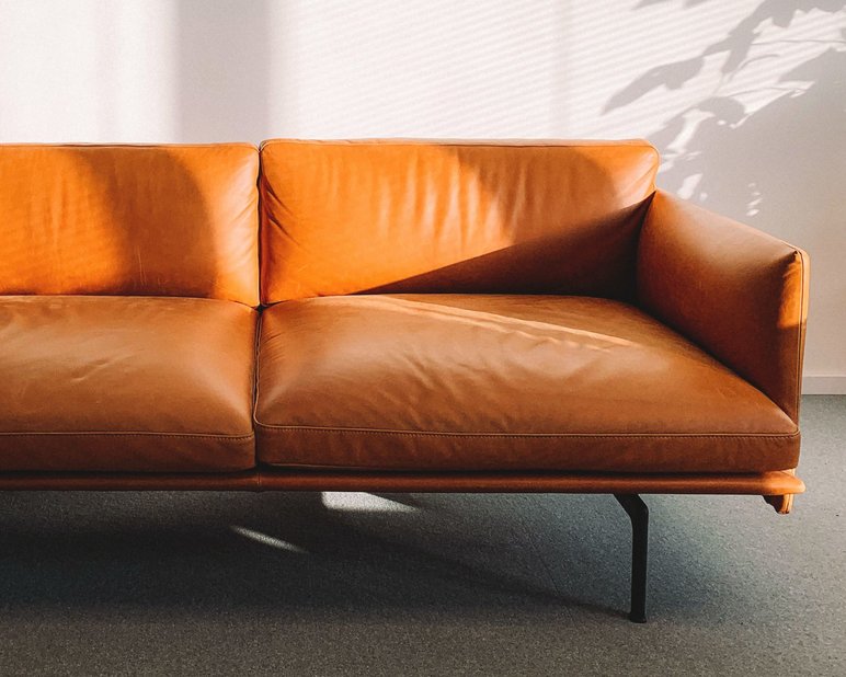 Light brown boned leather sofa partially covered in sunlight. 