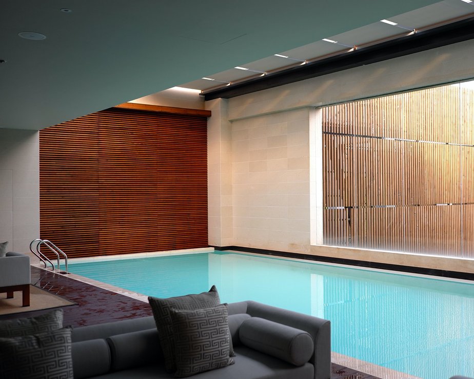 Modernist interior swimming pool with sleek wooden panels and grey furniture 
