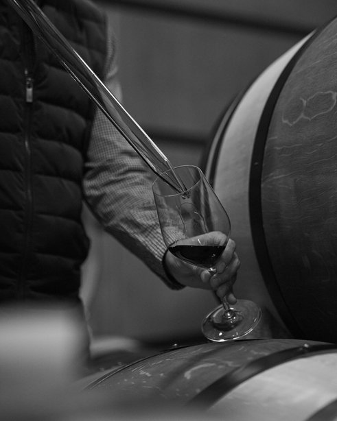 Man extracts wine from an oak barrel in Tenuta Luce's wine cellar