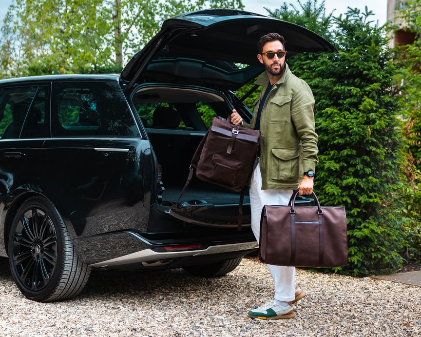 Fashionable an removing two brown soft leather bags from car boot