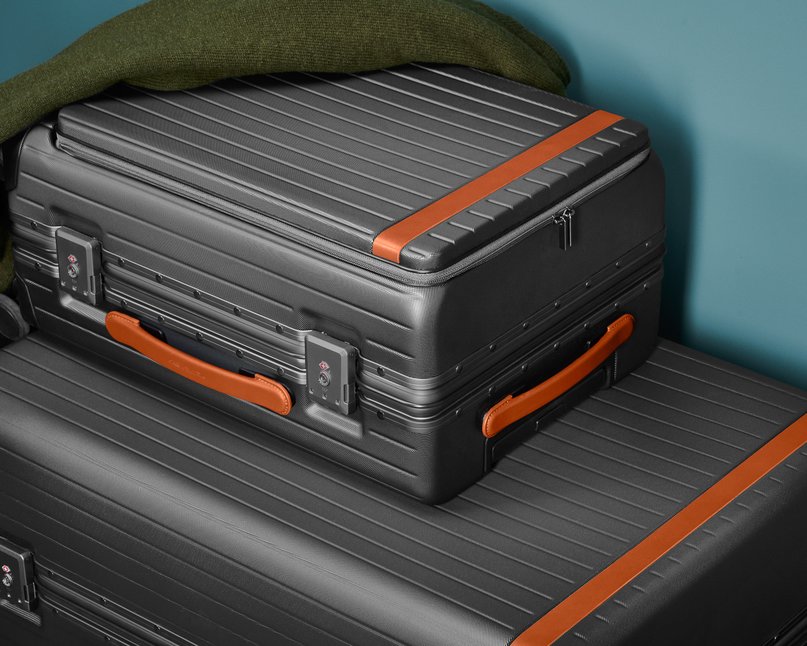 Two grey polycarbonate suitcases stacked on top of one another