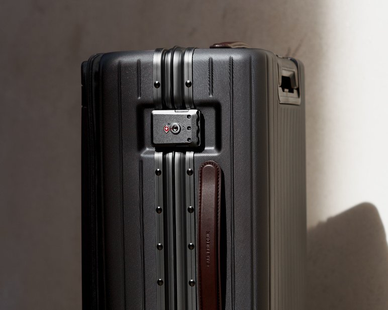 Two grey polycarbonate suitcases stacked on top of one another