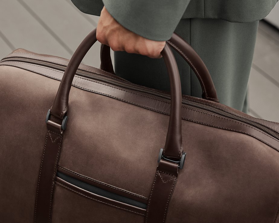 Man holding brown nubuck leather weekend bag