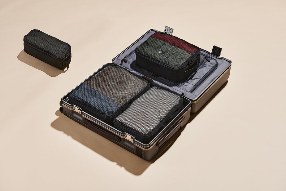 Open suitcase with three packing cubes inside and one sitting beside it