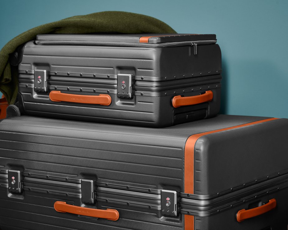 Set of matching grey polycarbonate luggage with cognac trims stacked 