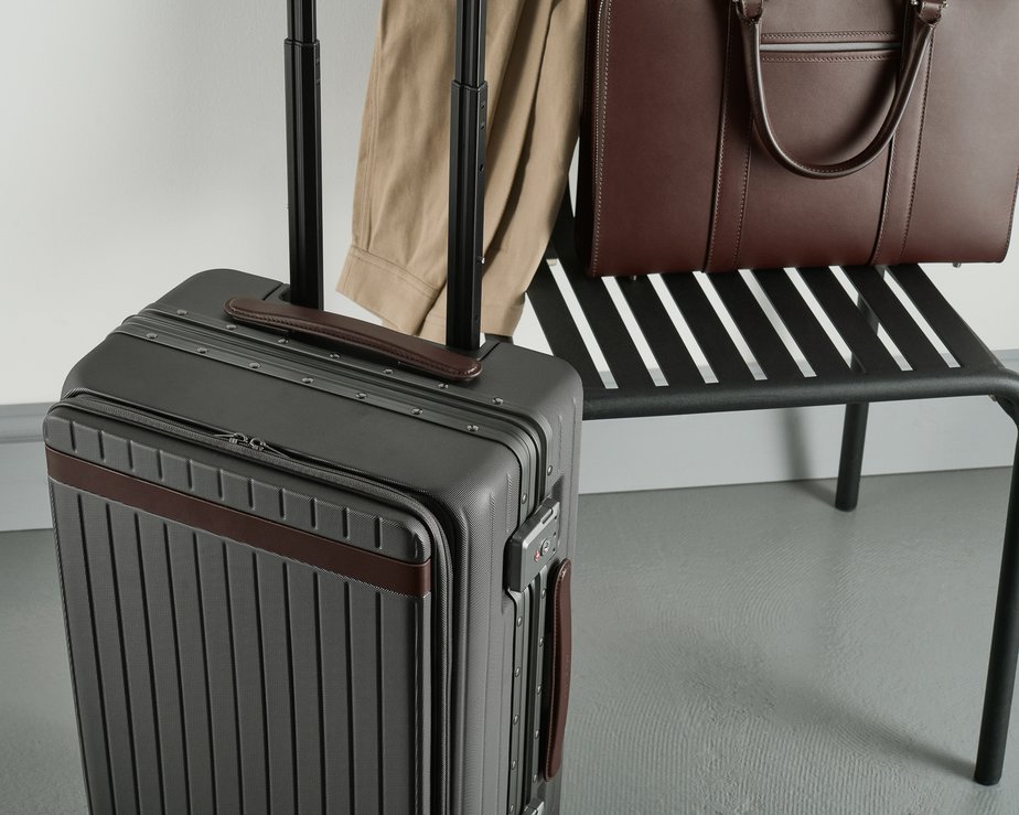 Grey polycarbonate luggage beside brown leather briefcase