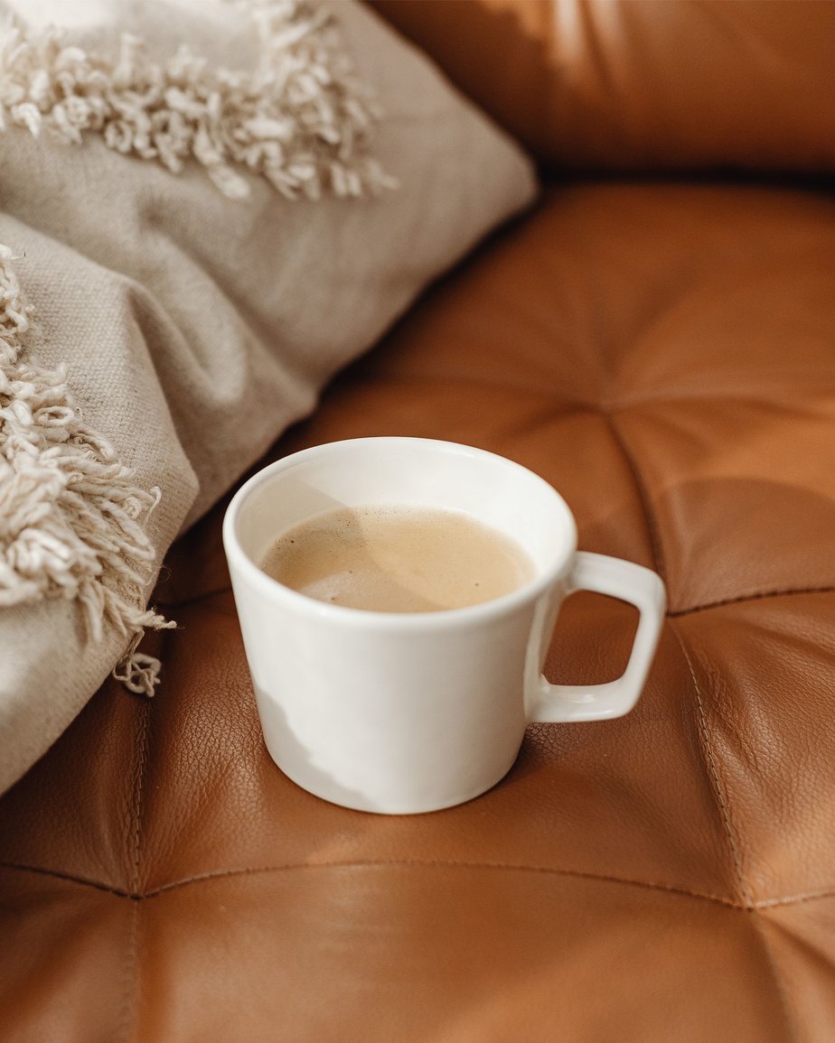 Mug of tea sitting on beige PU leather sofa with quilted pattern