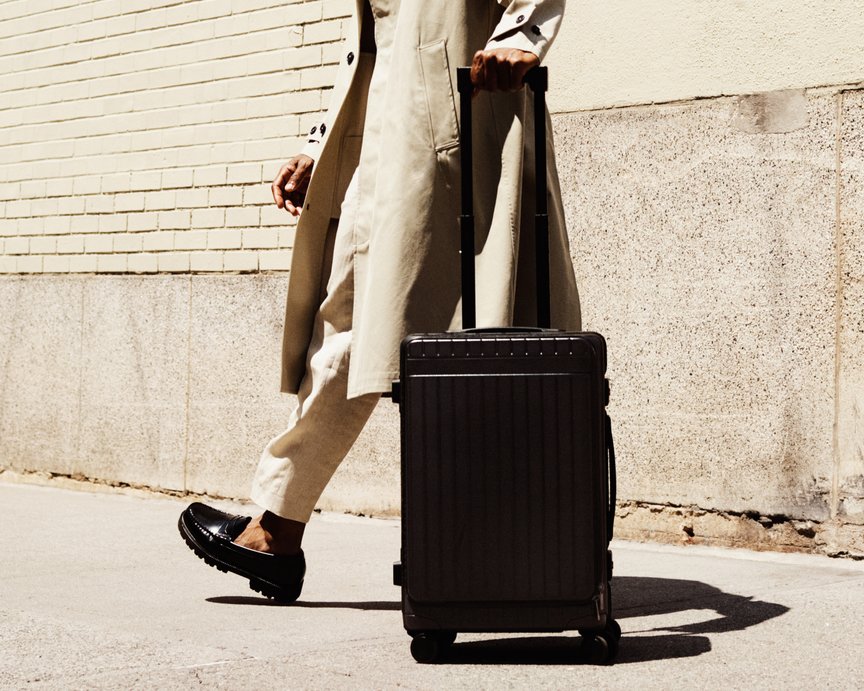 Stylish man walks down the street with Carl Friedrik all-black carry-on suitcase
