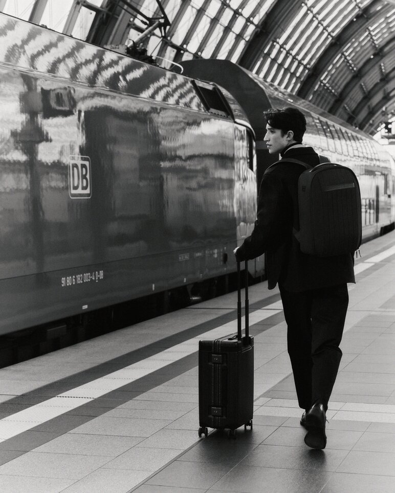 Man walks with a sleek carry-on beside train