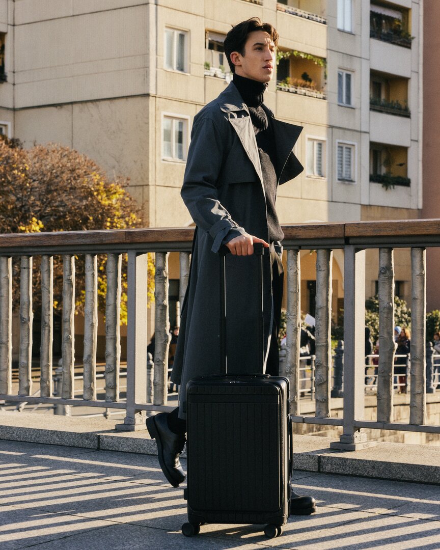 Lower half picture of man walking with sleek black luggage