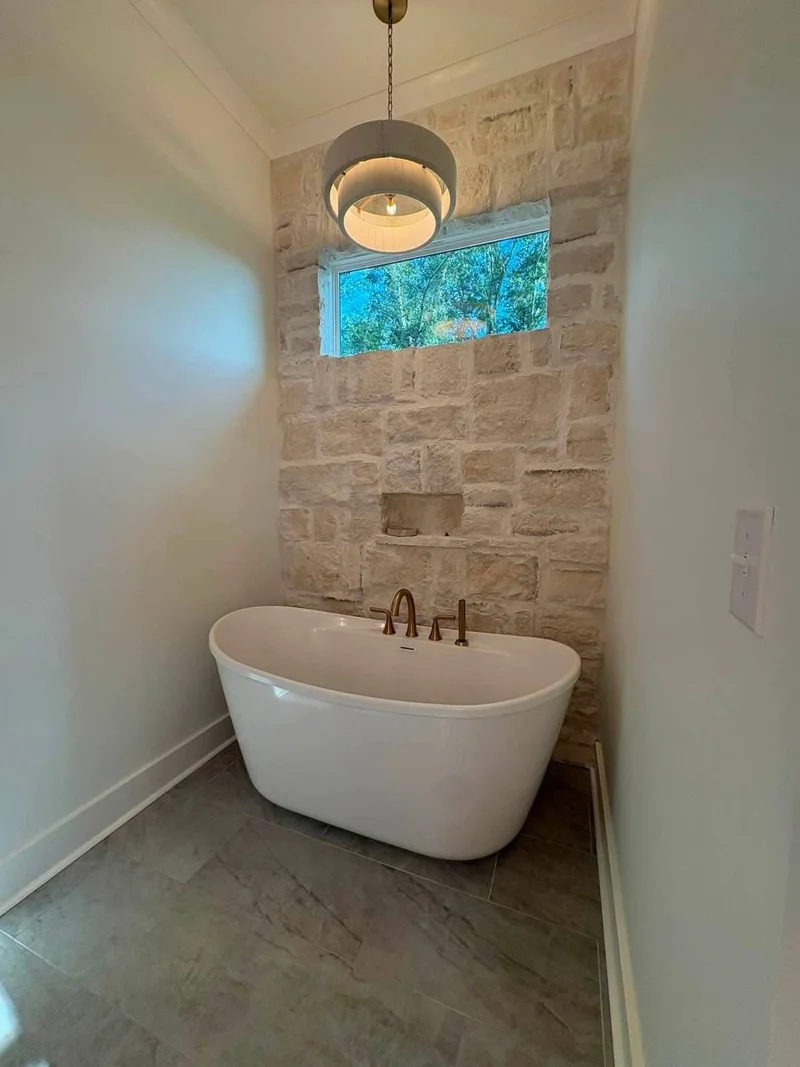 Freestanding soaking tub in a stone accent bathroom