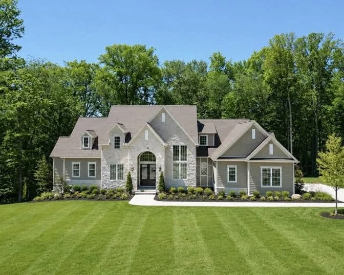 Custom light stone home exterior surrounded by mature trees