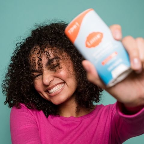 Woman holding solid stick deo and smiling