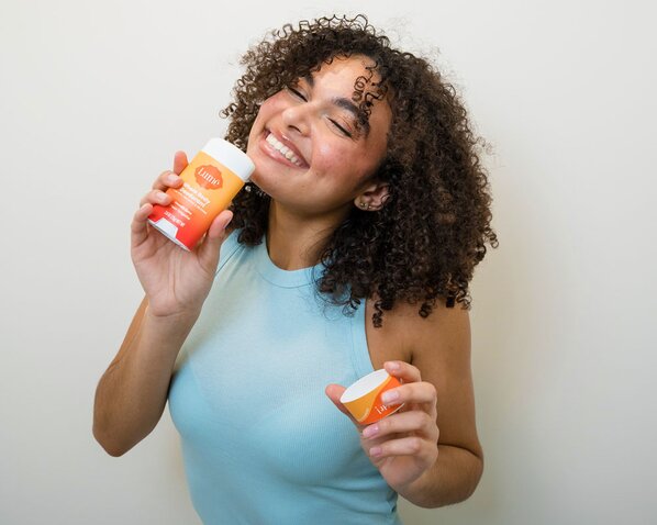 Woman holding Lume Deodorant Stick and smiling