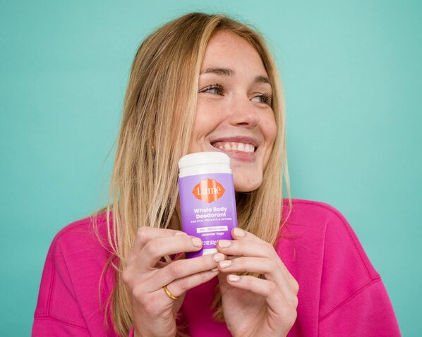 Woman holding Lume Deodorant Stick and smiling