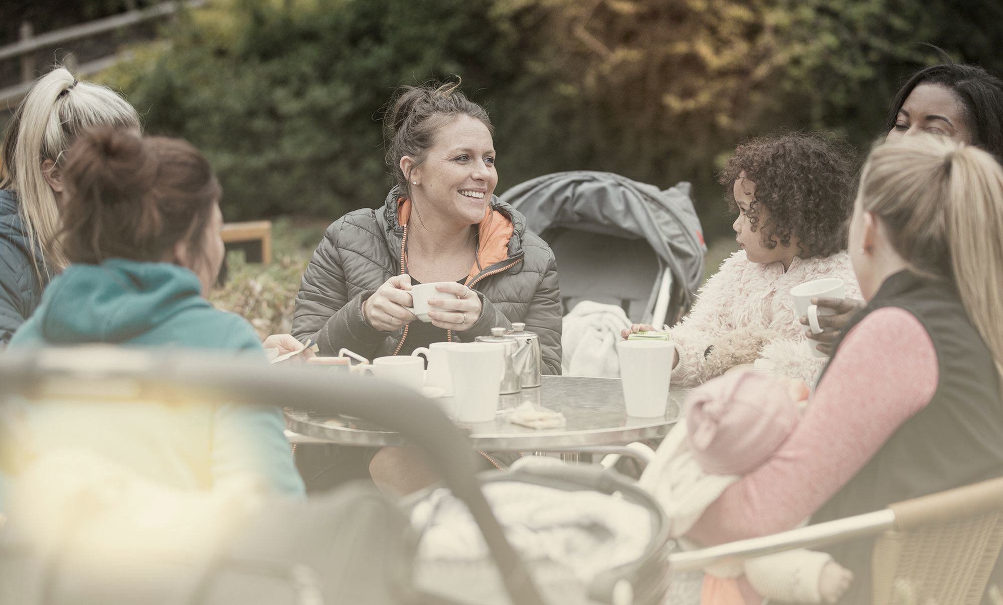 Woman sits with family and friends outside with light refreshments