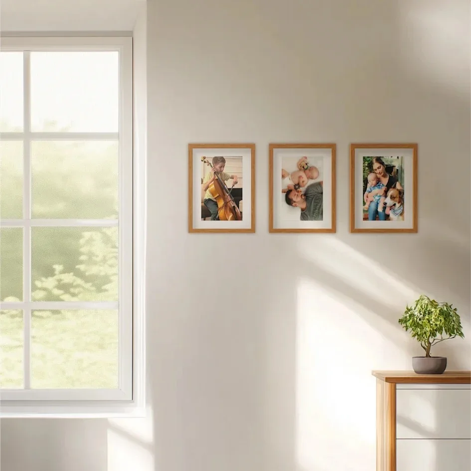 Three framed family photos on bright wall near window