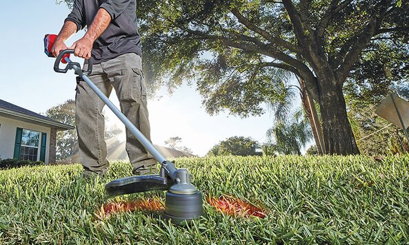 A man using a trimmer on a lawn.
