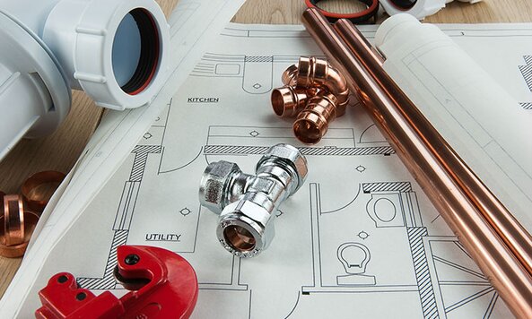 A collection of plumbing supplies and pipes on blueprints.