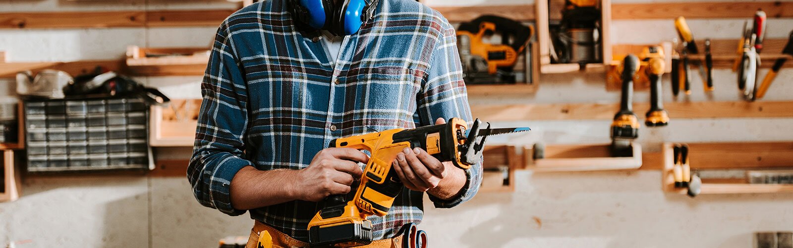 A pro holding a cordless reciprocating saw in their workshop.