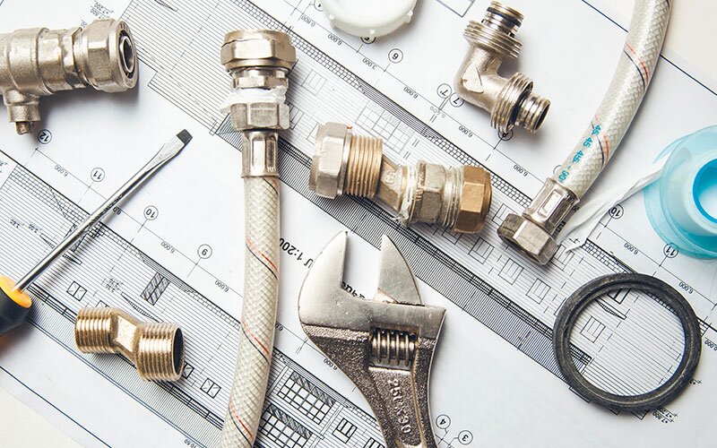 A selection of plumbing supplies resting on black and white blueprints.