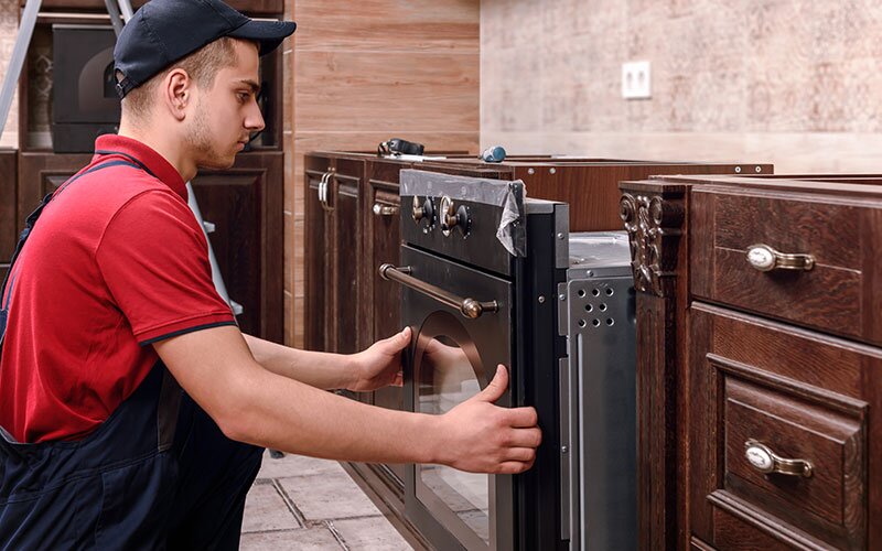 A worker installs a stove in a kitchen being renovated.