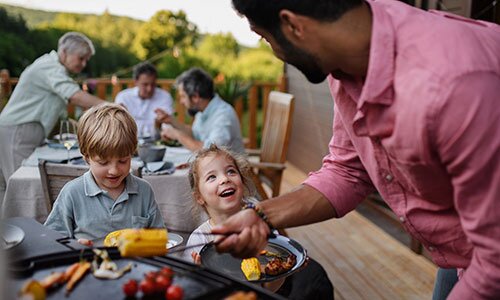 Children are excited for their veggies as they are served by the grill master.