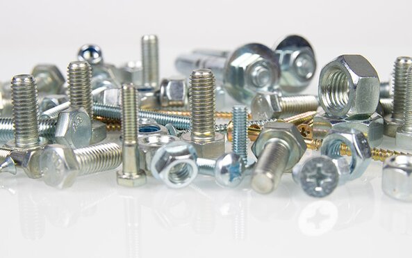 A group of screws, bolts, and washers on a reflective surface.